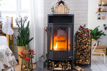 Metall black stove, burning hearth fireplace in white Festive interior of house is decorated for...