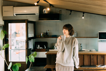 カウンターで温かい飲み物を飲む笑顔の女性