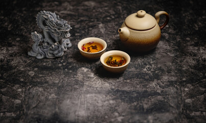 Beautiful dragon figurine, clay teapot and cups on dark table abstract background. Asian culture...
