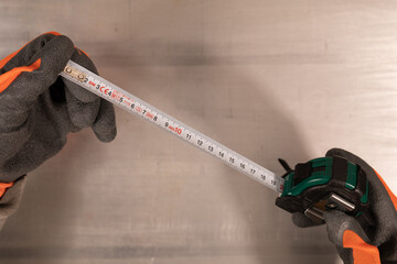 Gloved hand holding a measure tape isolated