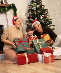 Obraz na płótnie Canvas Happy portrait Asian family Grand father, grandmother and grand daughter holding gift box with celebrating Christmas at home 