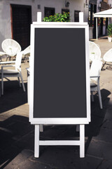 Empty copy space restaurant menu. Mockup chalkboard on street. White paint wooden frame. Sunlight and shadow.