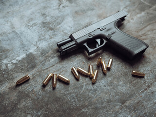 Hand gun with ammunition on dark background. 9 mm pistol military weapon and pile of bullets ammo at the metal table.