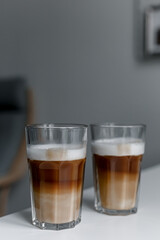 Set with two tall glasses of hot aromatic espresso coffee with cream poured over on gray background. Banner design. 