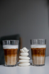 Set with two tall glasses of hot aromatic espresso coffee with cream poured over on gray...
