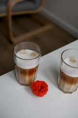 Set with two tall glasses of hot aromatic espresso coffee with cream poured over on gray...