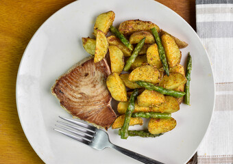 tuna steak with potato wedges  served with asparagus on top