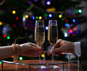 Male female hand holding glasses champagne New Year tree....