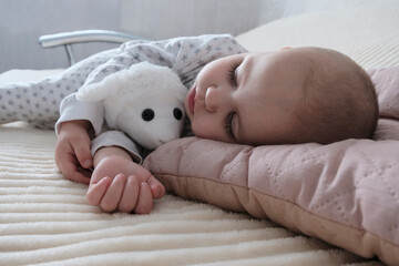 A cute baby, a child, a girl of European appearance, in a light light jumpsuit, is sleeping in the...