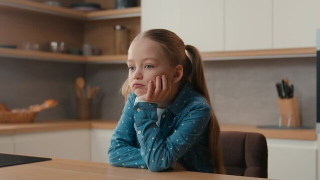 Moving camera sorrow grief worried little offended Caucasian sad upset bored child girl schoolgirl orphan unhappy lonely kid at home kitchen alone depressed stressed daughter sadness family quarrel