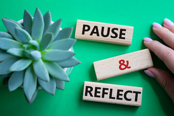 Pause and Reflect symbol. Concept words Pause and Reflect on wooden blocks. Beautiful green...