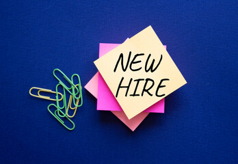 New Hire symbol. Orange steaky note with concept words New Hire. Beautiful deep blue background....