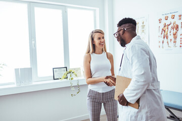 Smiling young male doctor shake hand close health insurance deal with female patient at...