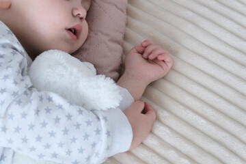 A cute baby, a child, a girl of European appearance, in a light light jumpsuit, is sleeping in the...