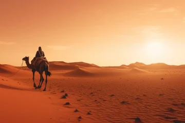 Rolgordijnen  a man riding on the back of a camel in the middle of the sahara desert at sunset or dawn with the sun shining on the horizon behind the sand dunes. © Nadia