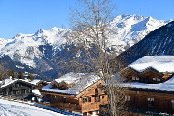 Winter scenery with chalets on the slopes of French alps. 