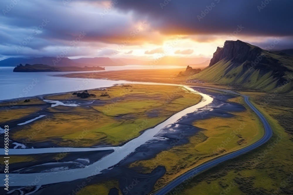 Poster an aerial view of a river running through a lush green field with mountains in the background and a 