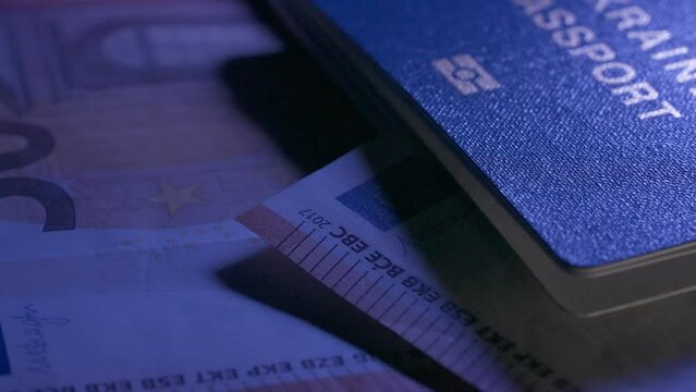 Passport and migration creative advertising concept. Close up of a human identity document and paper money. Euro banknotes and Ukrainian passport are laid out on the table.