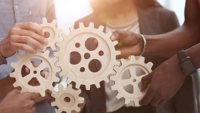 Efficient business team connects wooden gears into one