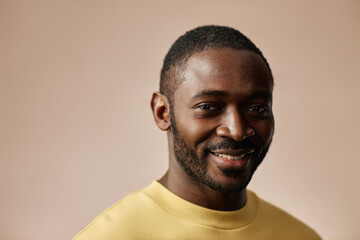 Minimal portrait of adult Black man looking at camera in studio against neutral background, copy...