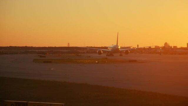 Plane drive into the gate at terminal at Chicago International Airport. Wide shot at sunset time