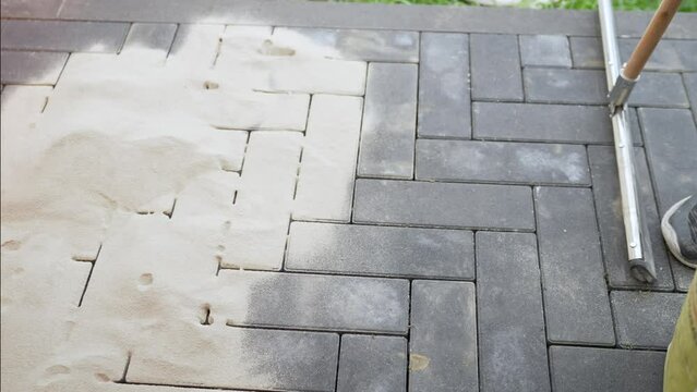 The process of laying garden stone tiles for a path in a country house or dacha. The master's hands fill the path with sand. Special sand for paving slabs.