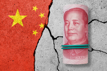 One hundred yuan note on a cracked concrete background. China finance, real estate and debt crisis....
