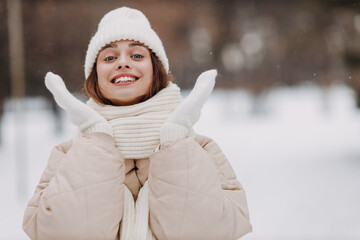 Happy smiling young woman portrait dressed coat scarf hat and mittens enjoys winter weather at...