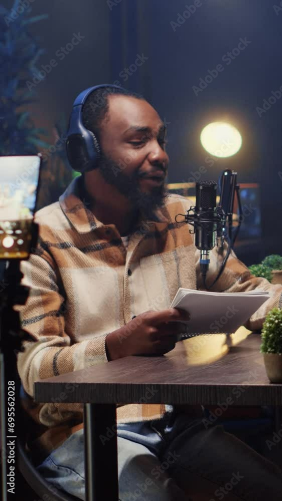 Poster vertical video man recording podcast using smartphone attached to tripod and high tech microphones t