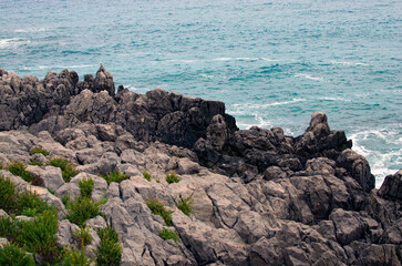 Scenic seascape of a rocks and cliffs into the waves of turquoise water of the Tyrrhenian sea near Cefalu, Sicily, Italy. Sea and rocks. Natural composition. Travel and tourism concept
