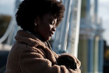 Smiling curly black woman enjoying winter sun outdoors.