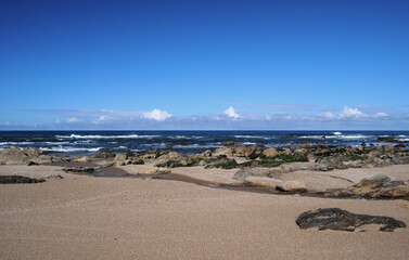 Landscape of a beach, ocean, sand rocks and sky with clouds, spring morning