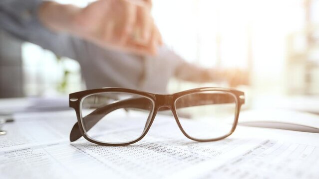 office desk with glasses and financial report