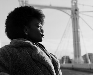 Monochrome portrait of young woman posing on bridge.