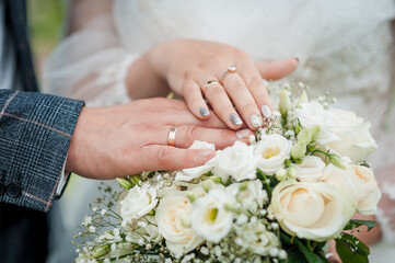 Obraz na płótnie Canvas Hands of the bride and groom on a wedding bouquet