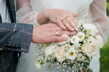 Hands of the bride and groom on a wedding bouquet