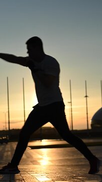A man trains boxing at sunset outdoors. Vertical video. 