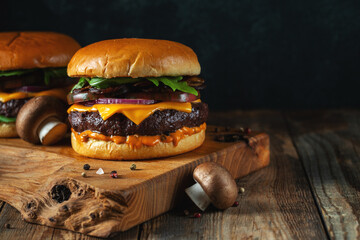 Two delicious homemade burgers of beef, cheese and mushrooms on an wooden table. With copy space