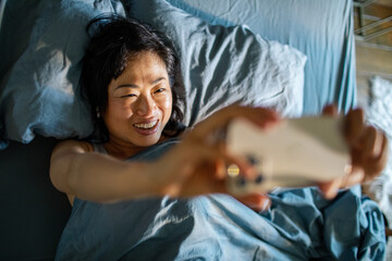 Smiling woman taking selfie in bed