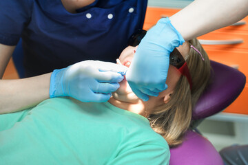 Little scared girl sitting in chair in dentist doctor office. Protective safety sunglasses....