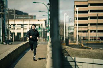Focused man jogging through the city streets on a sunny day