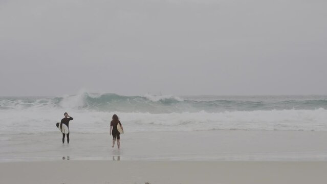 Surfista carregando sua prancha pela praia ate o mar. Cinematic 4k.
