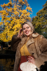 Smiling of friendly young woman posing in an autumn park.
