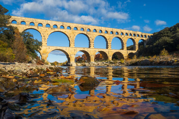 The Pont du Gard viewed from the river. Ancient Roman aqueduct bridge. Photography taken in Provence, southern France - obrazy, fototapety, plakaty
