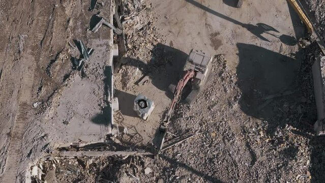 Drone shot of destroyed buildings. Demolition of the building. Excavator working rubbish in a demolition site. Top down shot