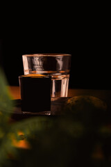 A glass of pure black coffee, surrounded by green leaves, coffee beans on the table, accompanied by a glass of refreshing water, ideal to start your day