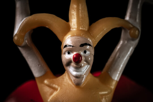 Creepy dirty toy jester in the dark. Scary face of a jester with a red nose on a black background