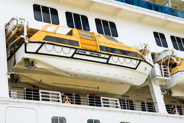 Side view of a large cruise ship with hanging lifeboat, emergency rescue boat