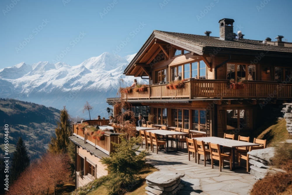 Poster a table and chairs outside of a building with a view of a mountain range and a snow capped mountain 