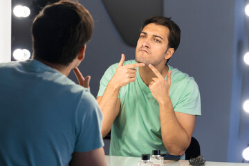 In front of the mirror, a man meticulously grooms himself, his reflection capturing the focused...